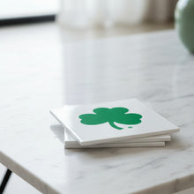Load image into Gallery viewer, Stack of white stone coasters with a green shamrock design on a brown surface