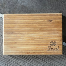 Load image into Gallery viewer, Wooden cutting board with 'Grad' engraving on a textured surface