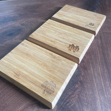 Load image into Gallery viewer, Wooden cutting board with engraved Notre Dame logo on a dark wooden surface