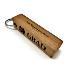 Load image into Gallery viewer, Our Notre Dame Grad Stadium Bench Wood Keychain measures 3.25" x .75" x .75".