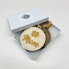 Load image into Gallery viewer, The ND Mom ornament is made from birch while the ND Dad ornament is made from walnut. Both ornaments in this Notre Dame Mom & Dad Christmas Ornament Set are laser-engraved and 3.25" in diameter.