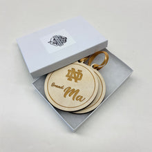 Load image into Gallery viewer, Each ornament in this Notre Dame Grandma & Grandpa Christmas Ornament Set is made from birch, laser-engraved, and 3.25" in diameter.