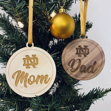 Load image into Gallery viewer, The ND Mom ornament is made from birch while the ND Dad ornament is made from walnut. Both ornaments in this Notre Dame Mom & Dad Christmas Ornament Set are laser-engraved and 3.25" in diameter.