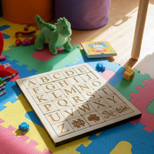 Load image into Gallery viewer, Wooden alphabet puzzle with letters and symbols on a light background featuring Notre Dame logos
