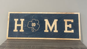 Our 24" x 9" x 1/2" Premium Notre Dame HOME Horizontal Sign comes in two color ways: Blue on Gold