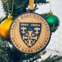 Load image into Gallery viewer, This Saint Mary&#39;s College Crest Christmas Ornament is made from stained birch, laser-engraved, and is 3.25&quot; in diameter. 

